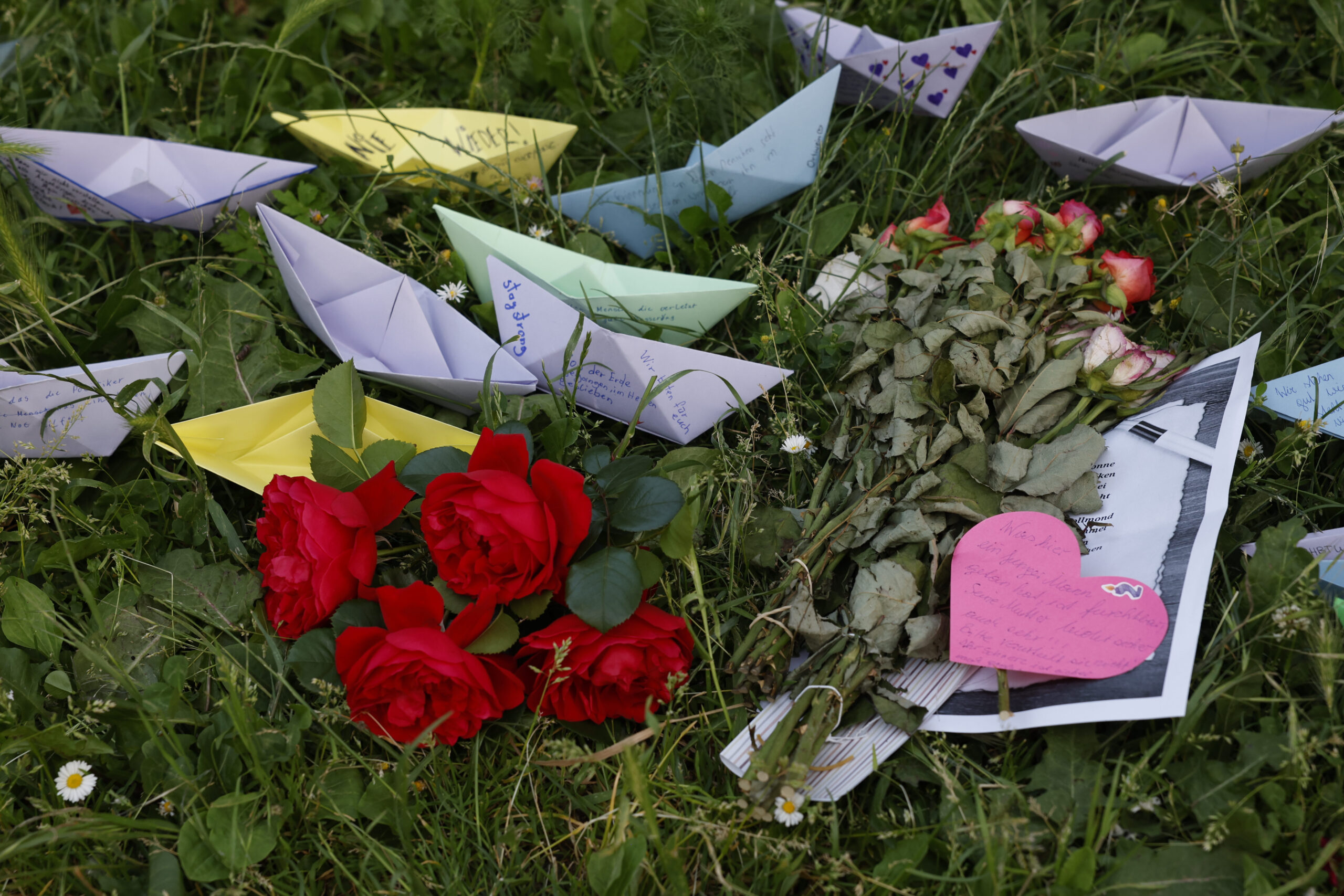 Rosen und Papierschiffchen liegen am Rasen